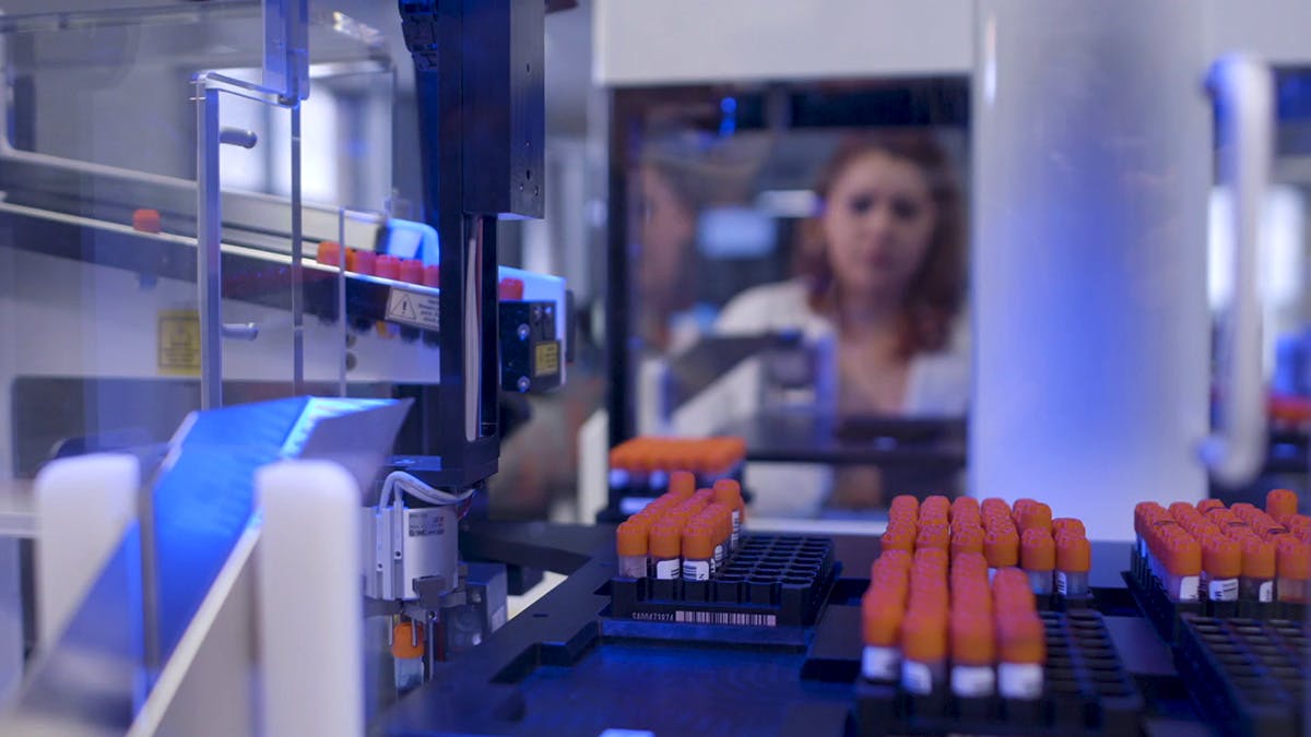a scientist in the Lumi lab holding a DNA array panel
