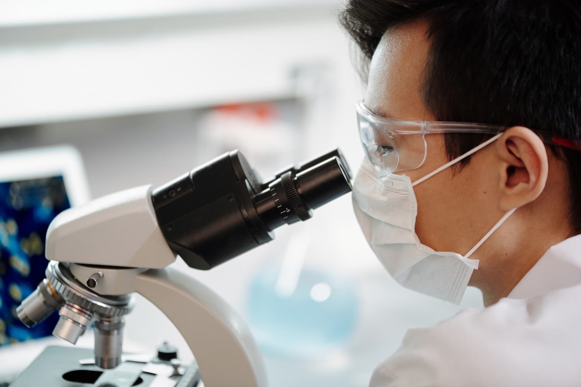 a close up photo of a man looking into a microscope