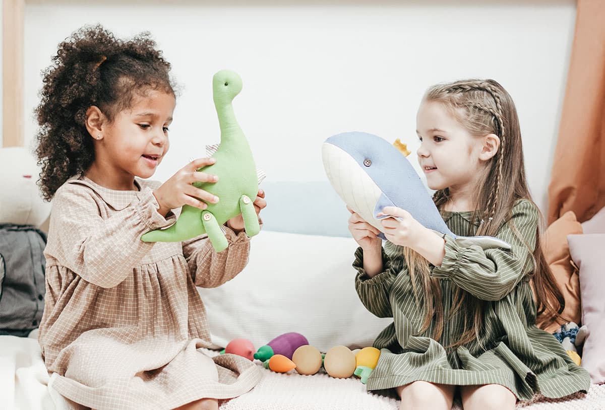 Two young children playing with soft toys