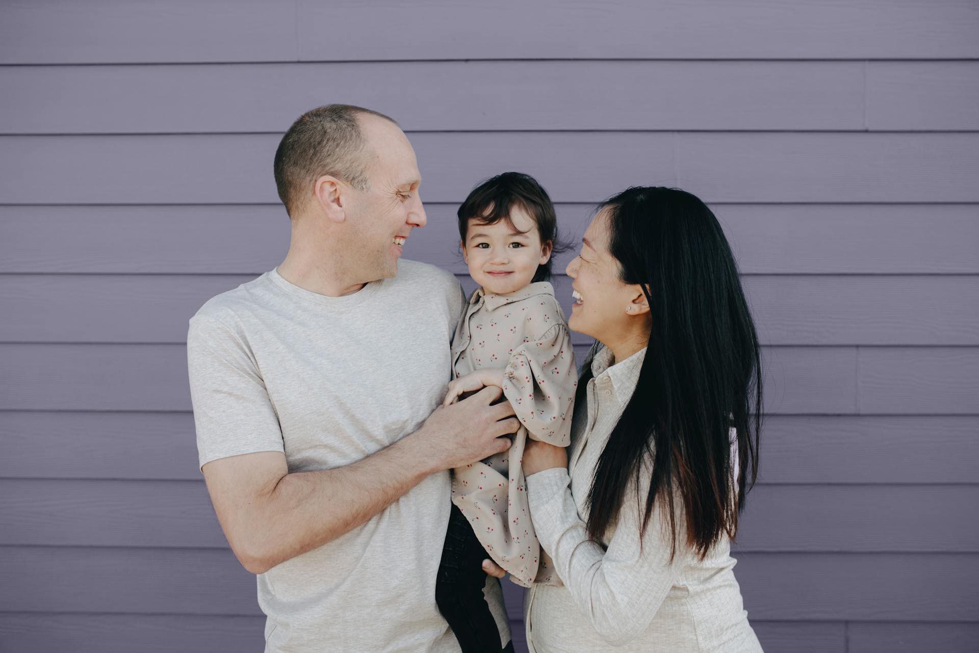 A smiling couple holding their young baby
